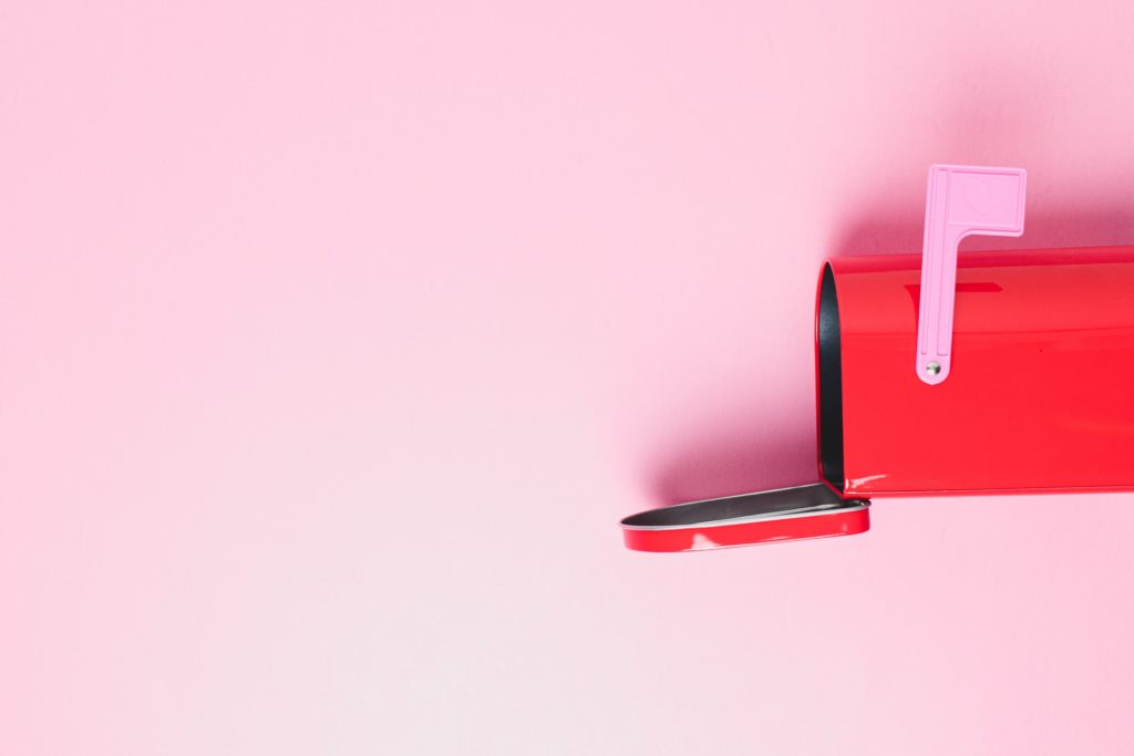 Pink background with open, red mailbox. Pink lever and black interior. 