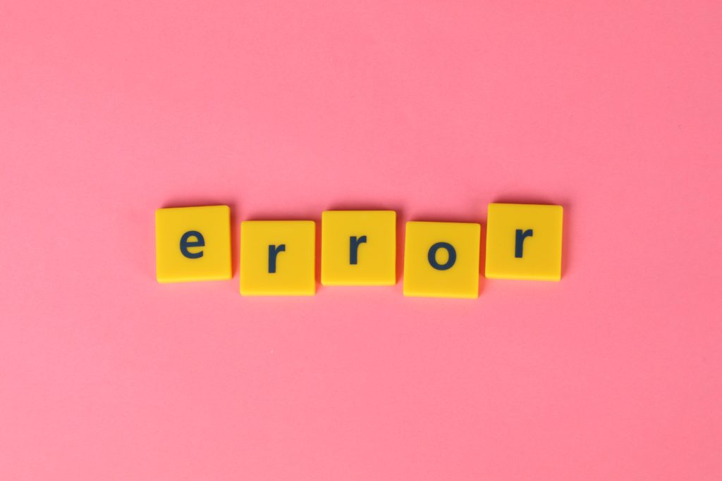The word "error" spelt out in yellow Scrabble tiles against a pink background
