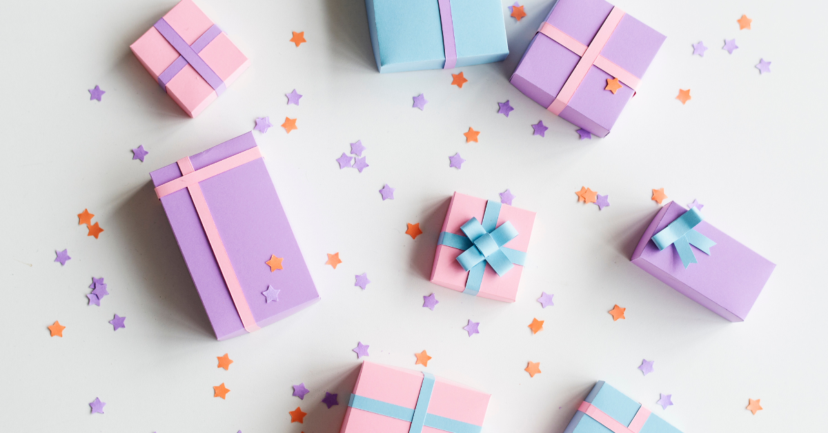 A collection of pink, purple, and blue gift boxes with ribbons and little stars as confetti beneath them