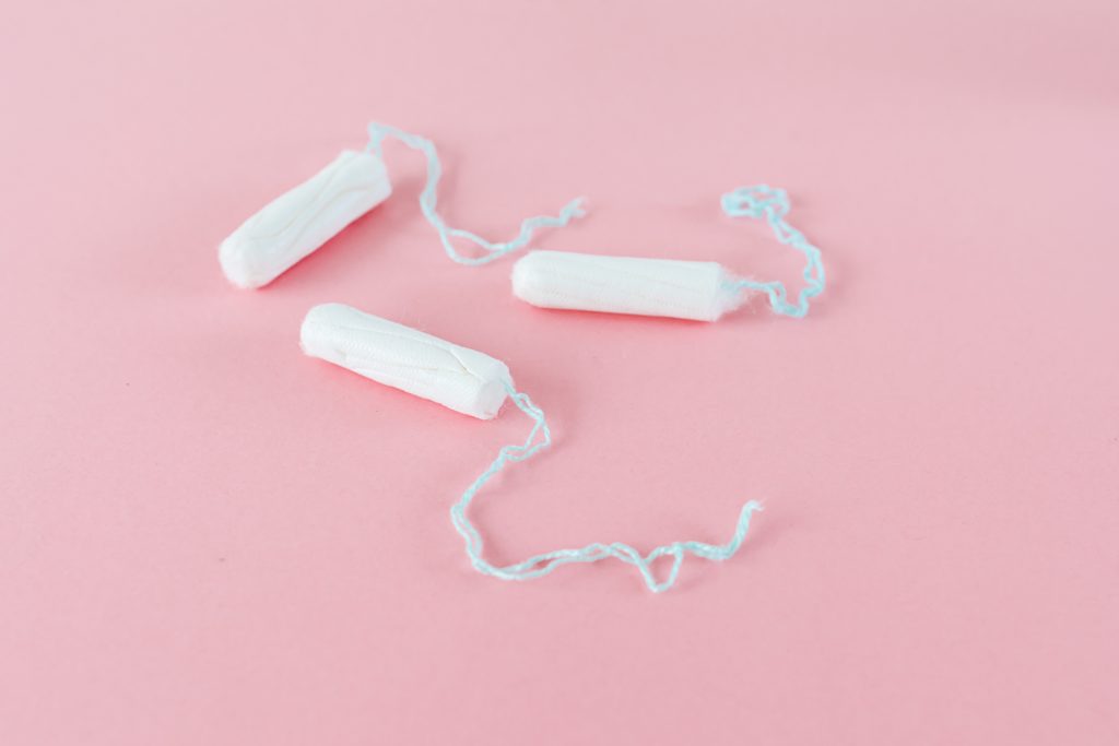 Three tampons on a pink background.