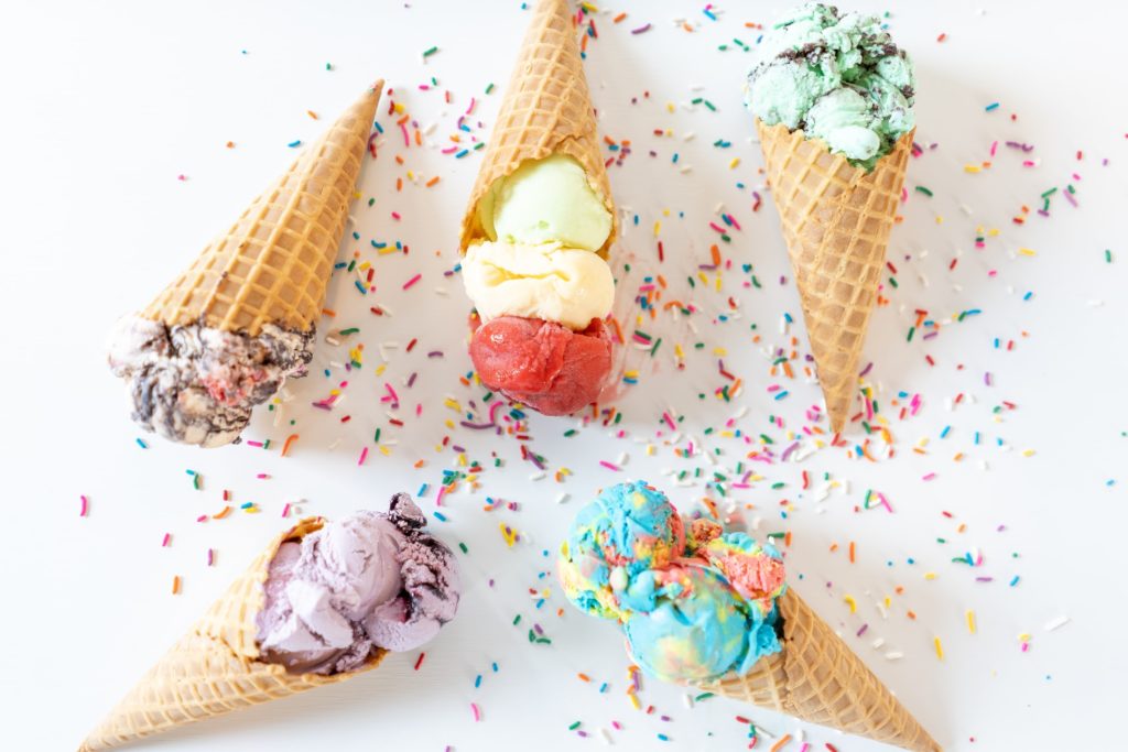 5 ice creams in waffle cones. There's bubblegum, mint-choc-chip, raspberry and vanilla, rum and raisin, and pistachio. There's sprinkles beneath all the cones.