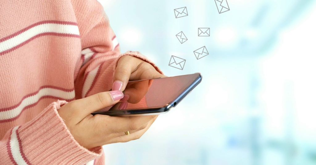 Woman in a pink and white striped jumper with a phone in her hand. Email symbols on the side. 