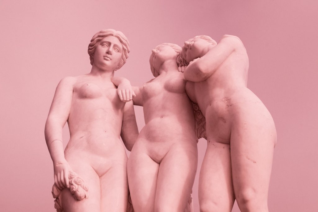 3 ancient greek statues of women in pink.